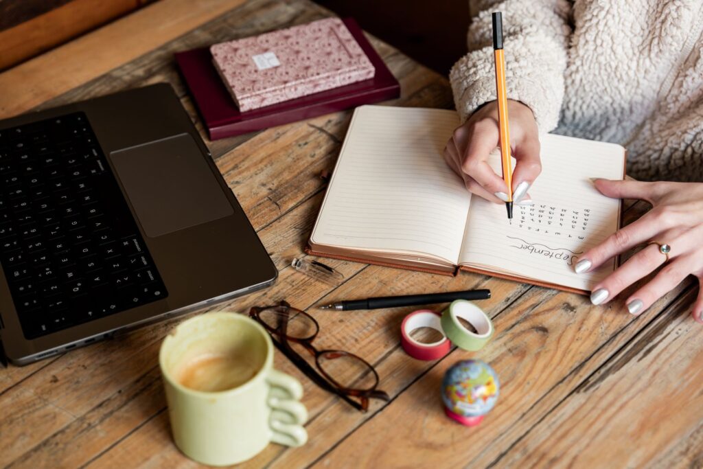 Woman planning in a notebook beside a laptop and coffee