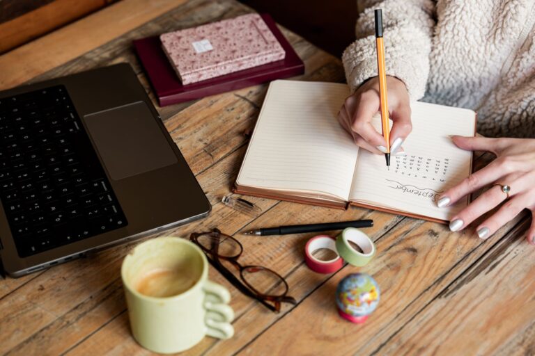 Woman planning in a notebook beside a laptop and coffee