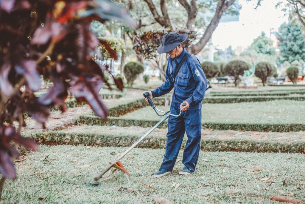 Landscaper trimming grass in a park