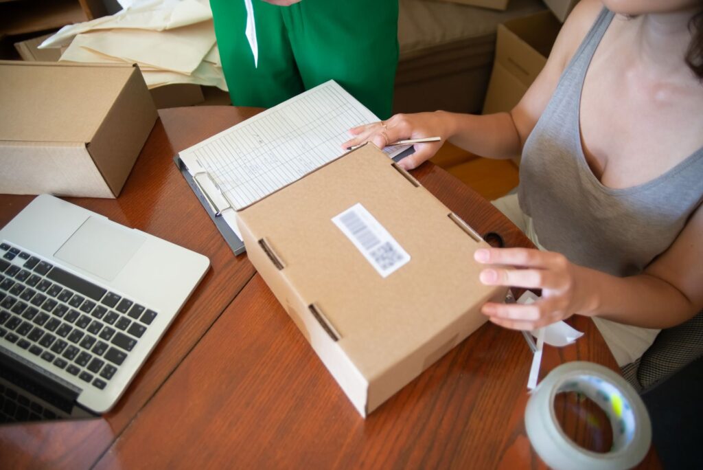 Two people packing online orders next to a laptop