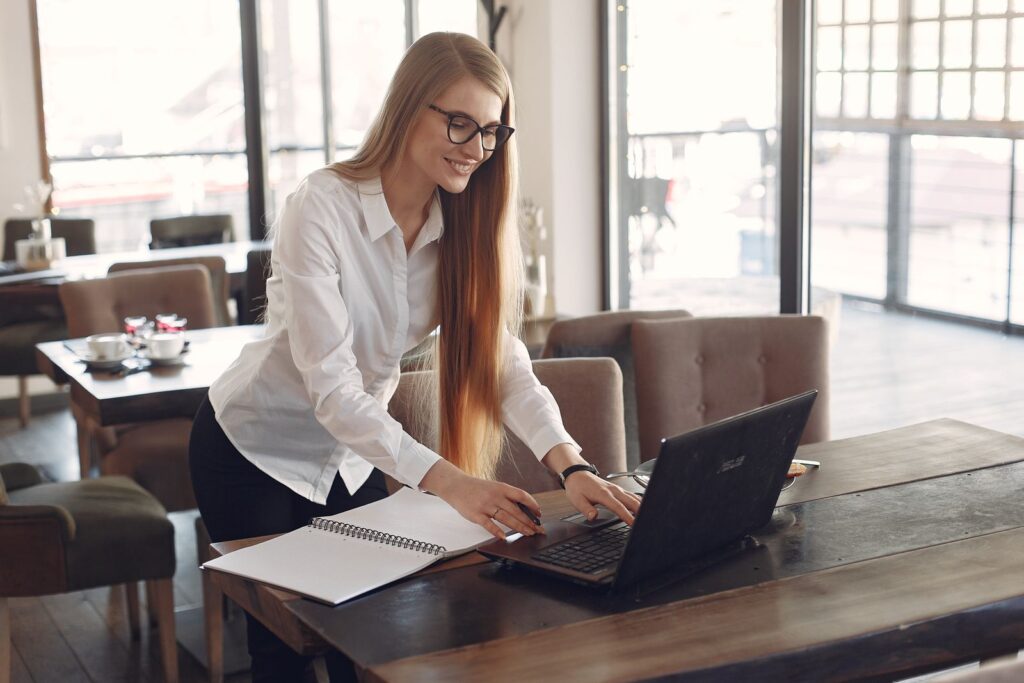 Young woman working on a side hustle with a laptop in a cafe