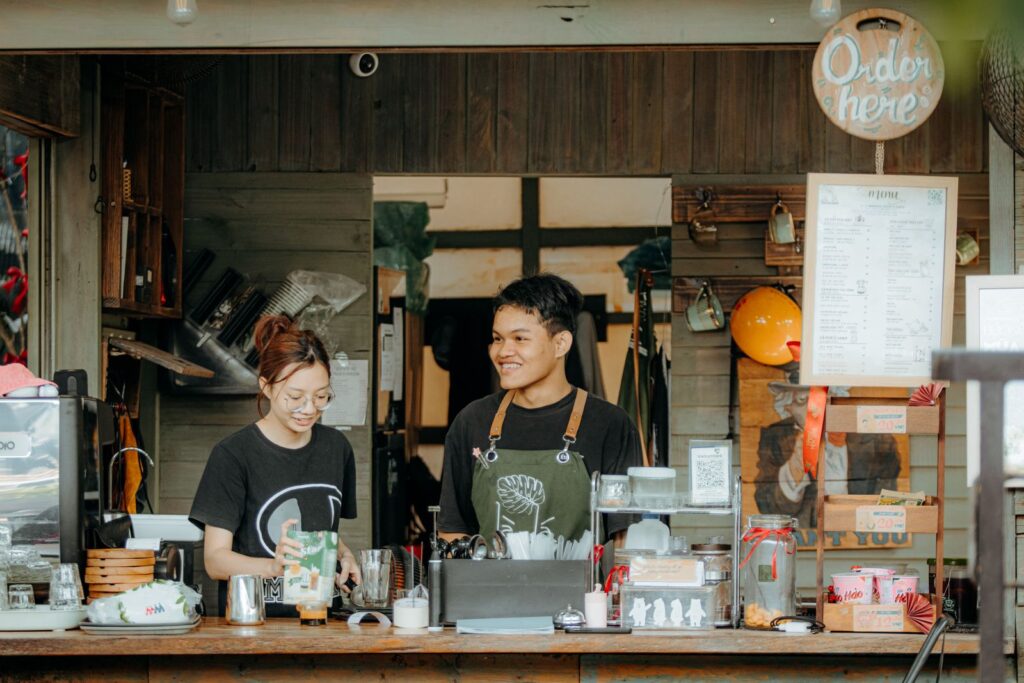 Two baristas behind the counter of a cozy small town coffee shop